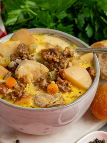 Image of crock pot sausage and potato soup in a bowl with a spoon in it.