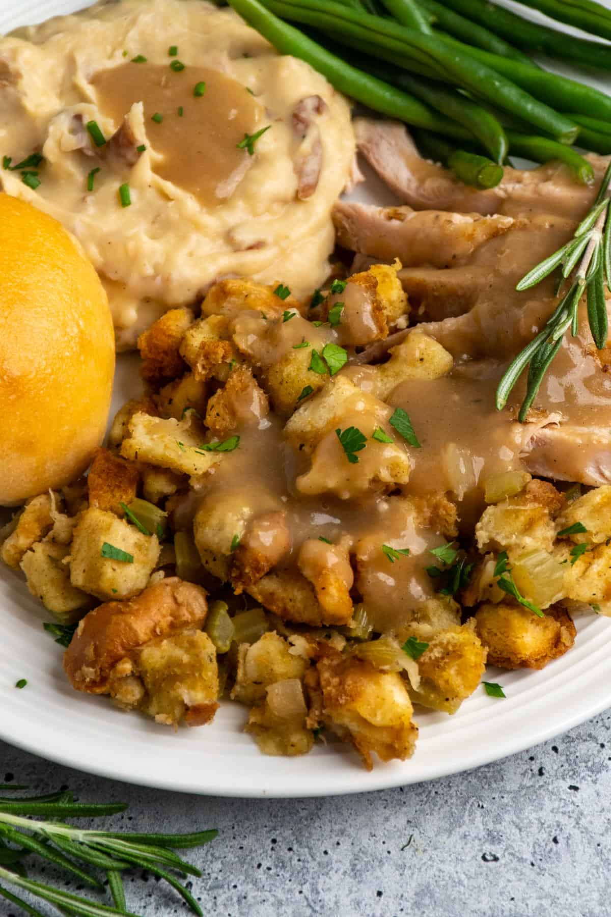 Stuffing on a plate covered in gravy and mashed potatoes in the background