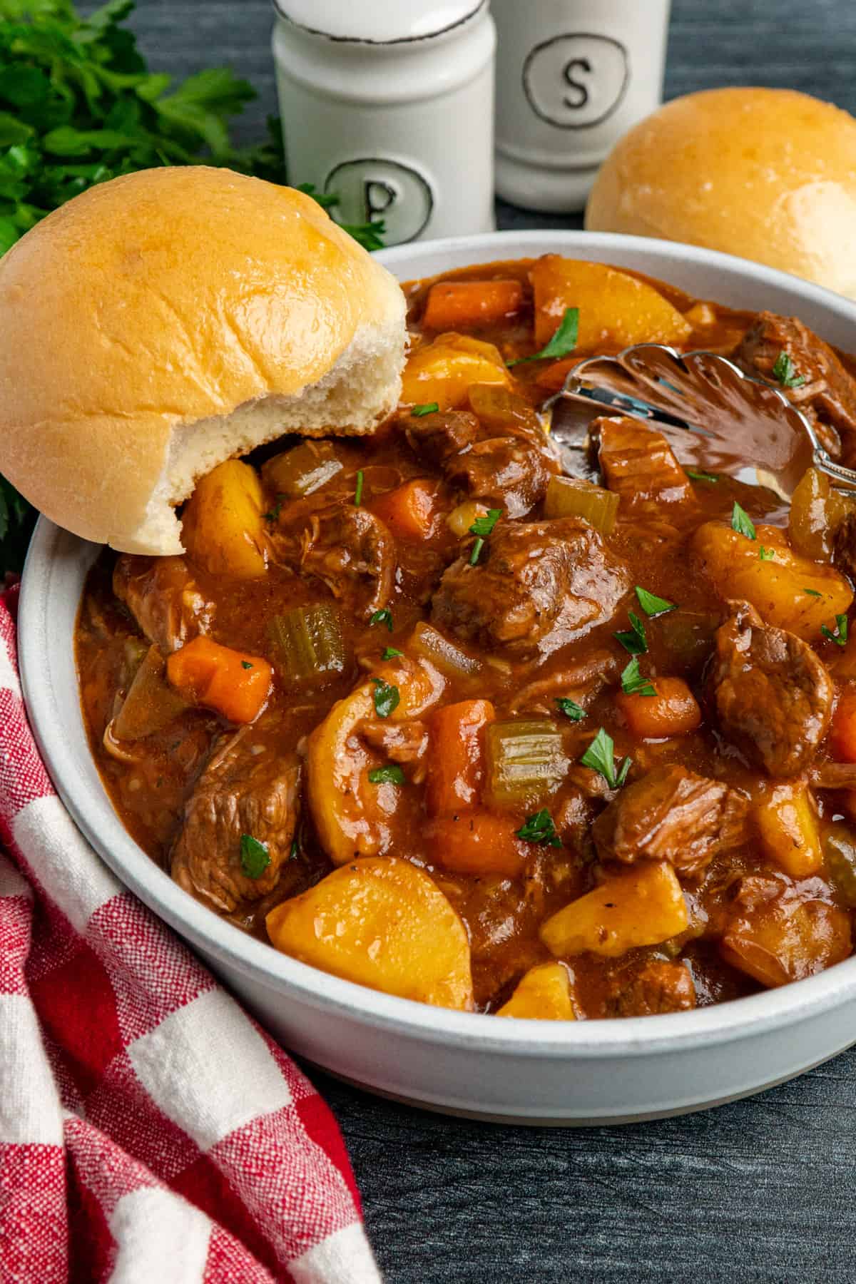 Close up of slow cooker beef stew in a bowl served with a roll
