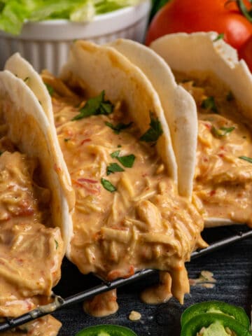 Close up of three slow cooker queso chicken tacos in flour tortillas