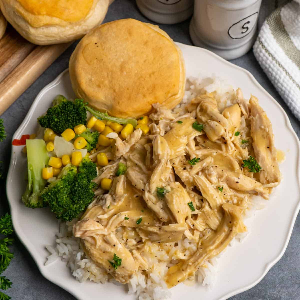Crock Pot chicken and gravy over rice on a white plate.