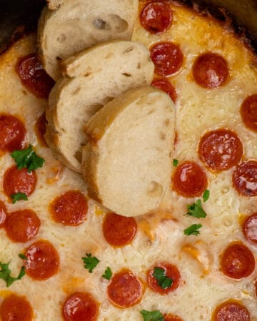 Close up of crock pot pizza dip with three pieces of bread on top