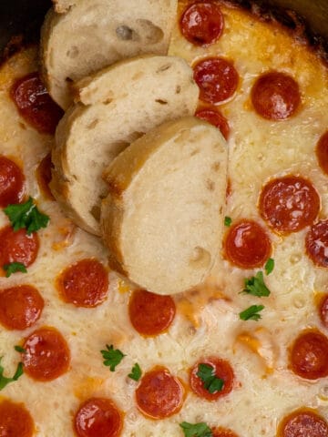Close up of crock pot pizza dip with three pieces of bread on top