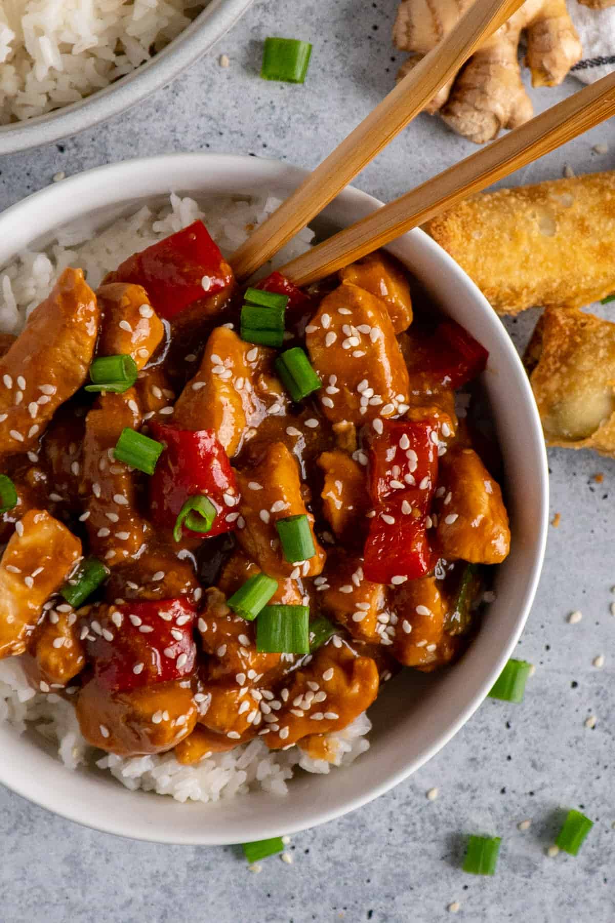 Crock Pot sesame chicken over a bowl of rice with red peppers.