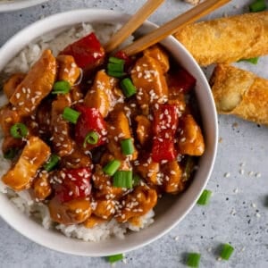 Crock Pot sesame chicken over a bowl of rice with red peppers.