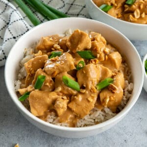 Slow cooker Thai peanut chicken in a bowl and garnished with green onions.