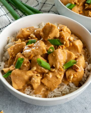 Slow cooker Thai peanut chicken in a bowl and garnished with green onions.