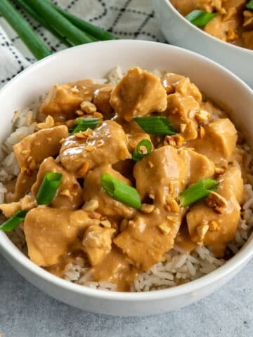 Slow cooker Thai peanut chicken in a bowl and garnished with green onions.