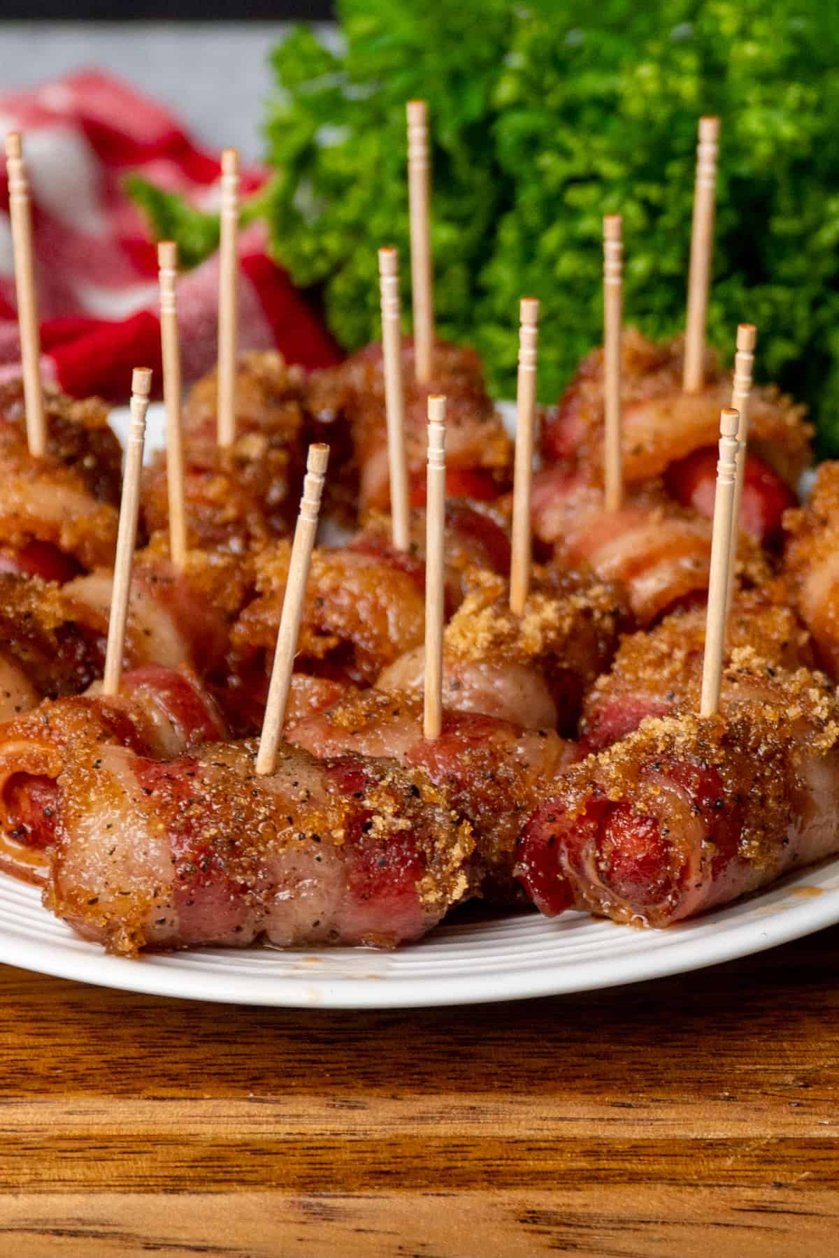 Close up of crock pot bacon wrapped little smokies on a plate with toothpicks.