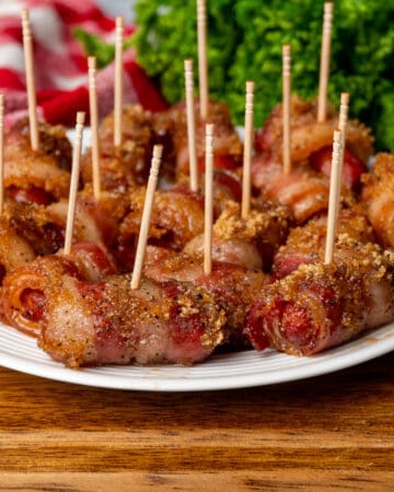 Close up of crock pot bacon wrapped little smokies on a plate with toothpicks.