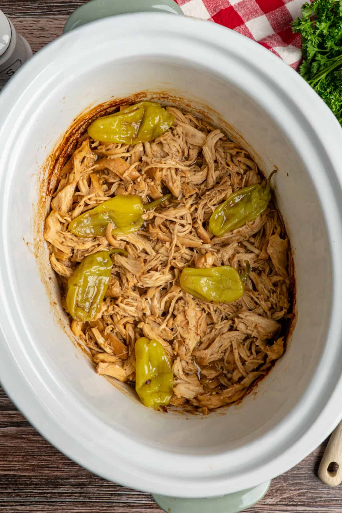 Overhead look at Crock Pot Mississippi Chicken in a white slow cooker.