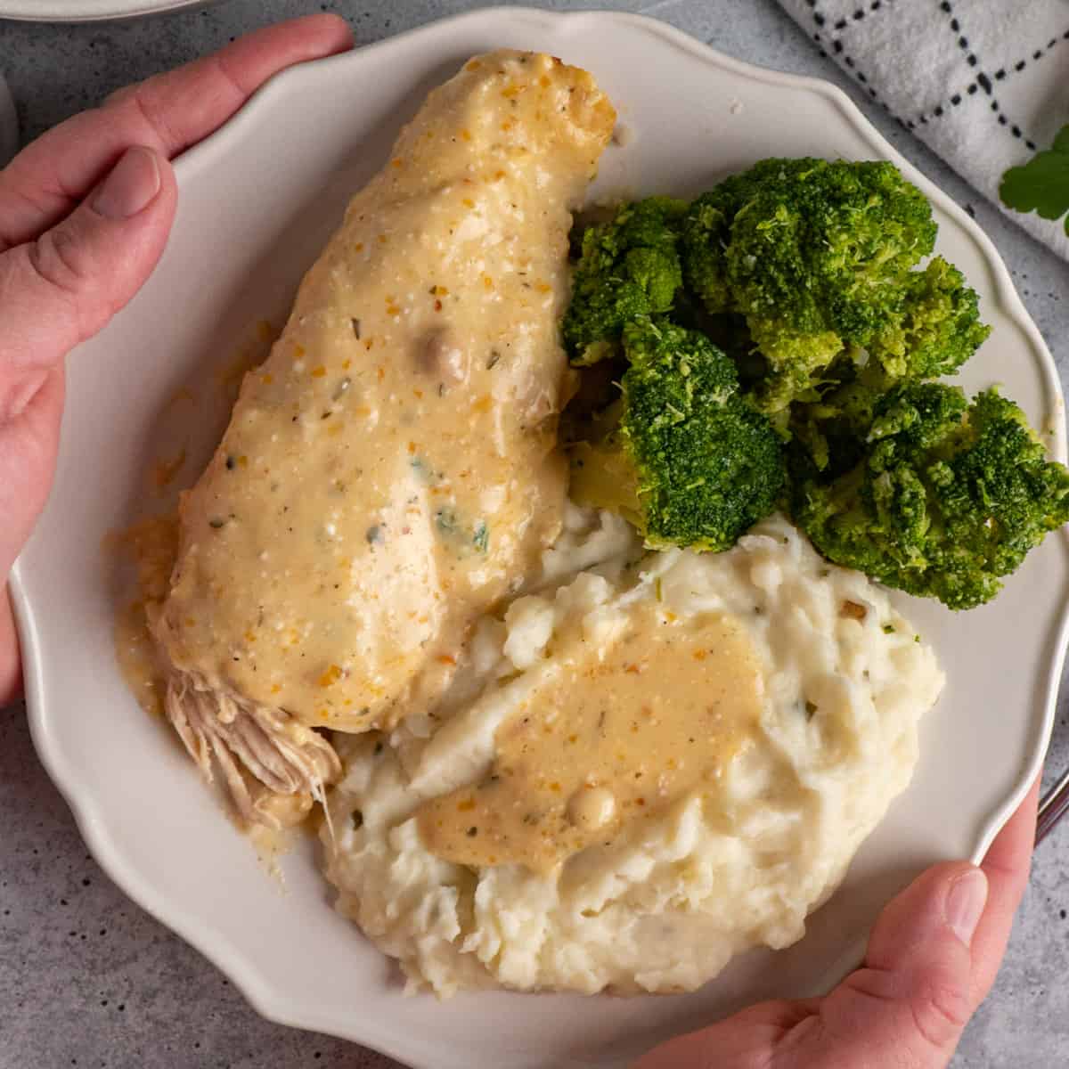 Crock pot ranch chicken on a plate with mashed potatoes and broccoli.