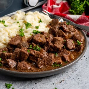 Crock Pot steak bites on a plate with mashed potatoes.