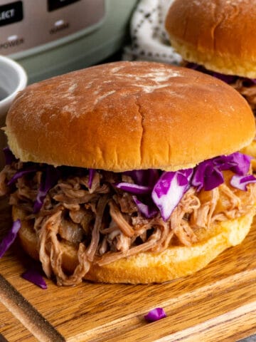 Slow cooker Hawaiian pulled pork on a bun and topped with cabbage.