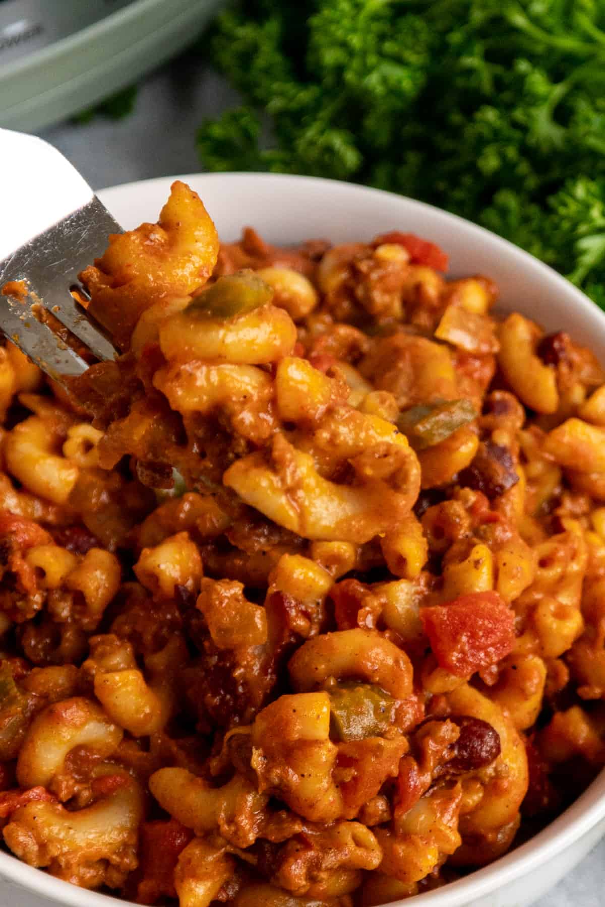 Chili mac on a fork over a bowl.