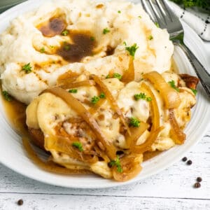 Crock Pot French onion chicken on a plate with mashed potatoes.