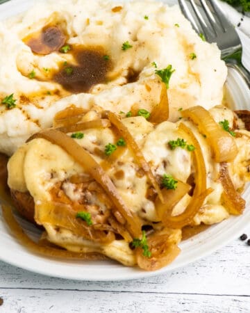 Crock Pot French onion chicken on a plate with mashed potatoes.