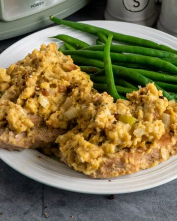 Crock Pot pork chops with stuffing on a plate with green beans.