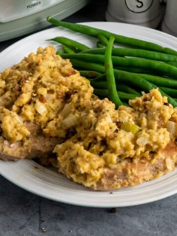 Crock Pot pork chops with stuffing on a plate with green beans.