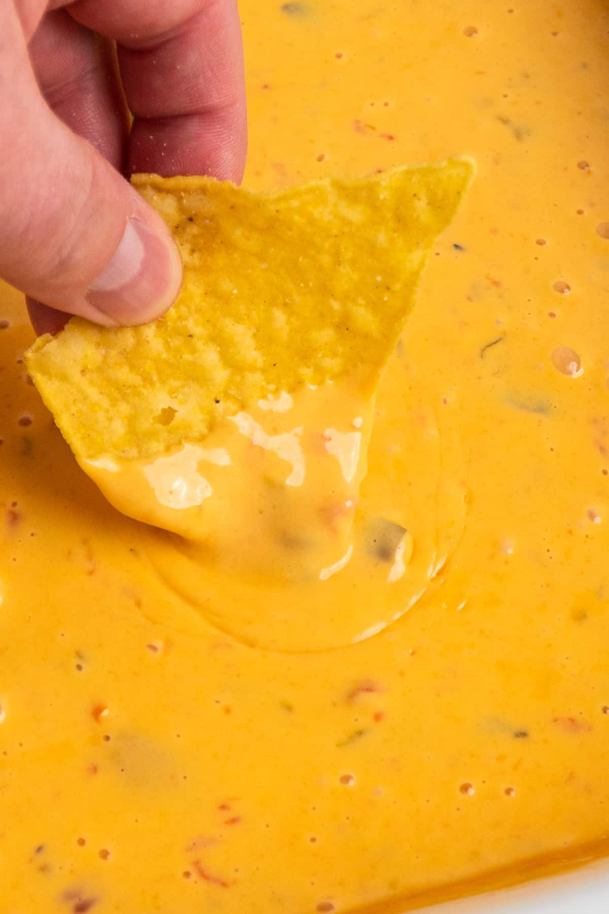 A chip being dipped into nacho cheese dip.