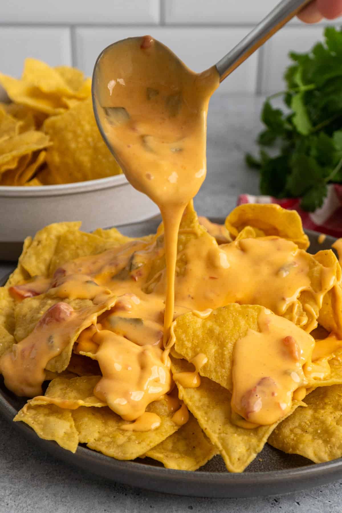 Crock Pot Velveeta cheese dip being poured over tortilla chips.