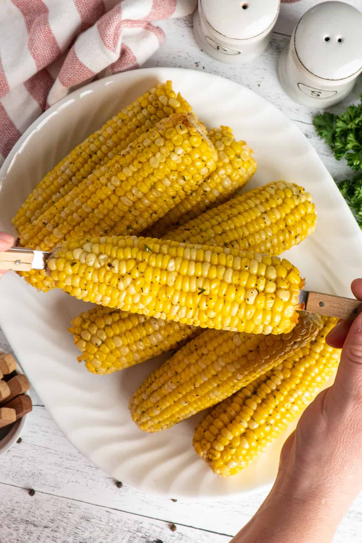 Hands holding a piece of crock pot corn on the cob.