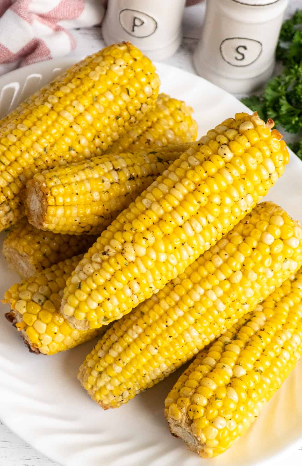 Freshly buttered corn on the cob stacked up on a plate.