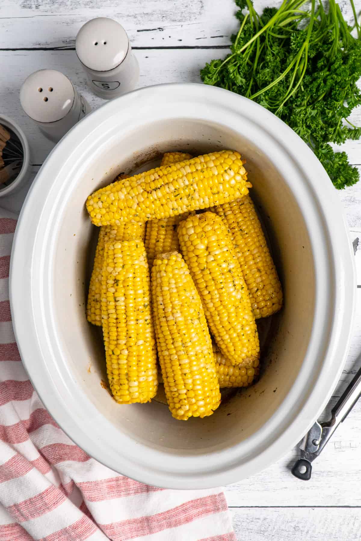 Corn on the cob in a white slow cooker.
