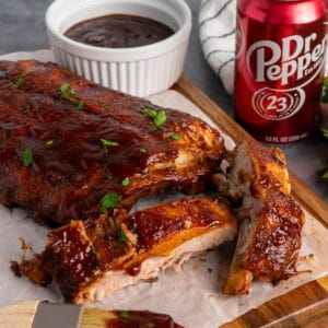 Close up of crock pot Dr. Pepper ribs on a wood cutting board.