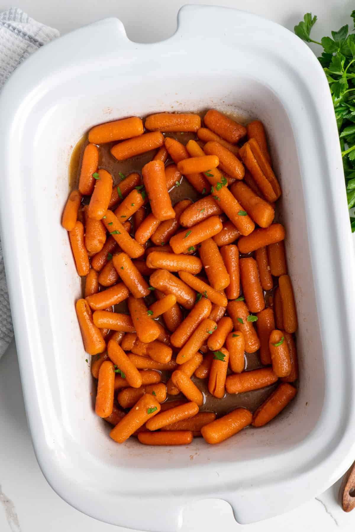 Honey glazed carrots in a white slow cooker.