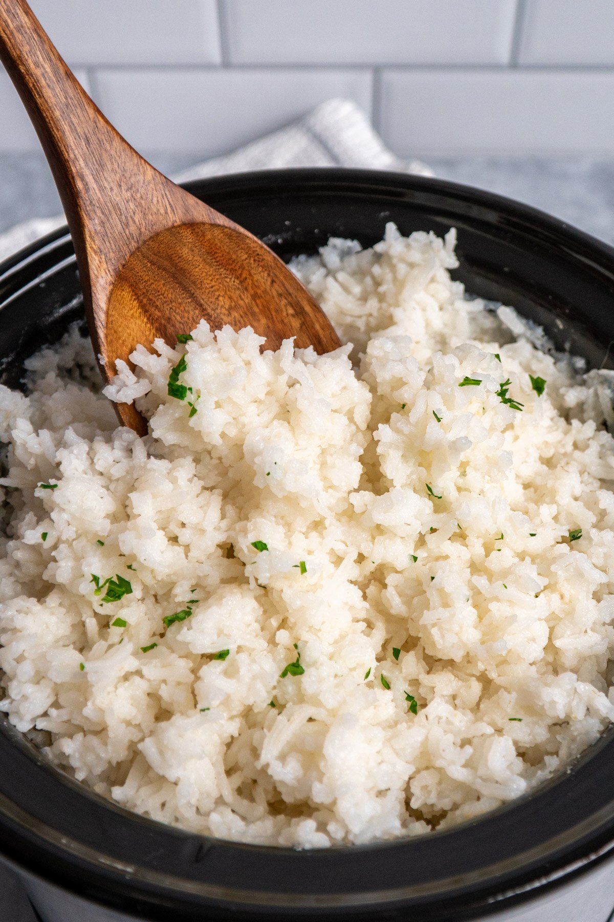 White rice in a crock pot with a wooden spoon.