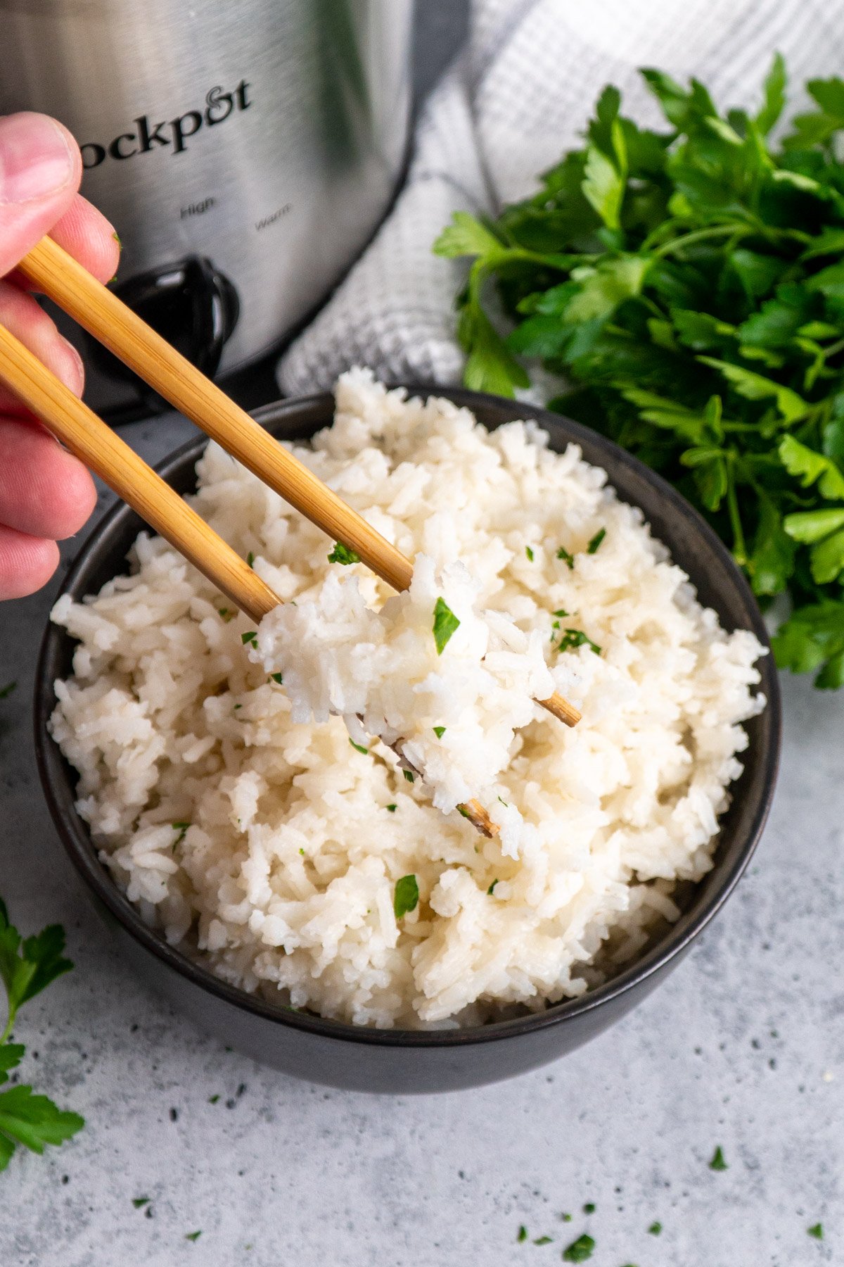 Chopsticks holding cooked rice over a bowl.