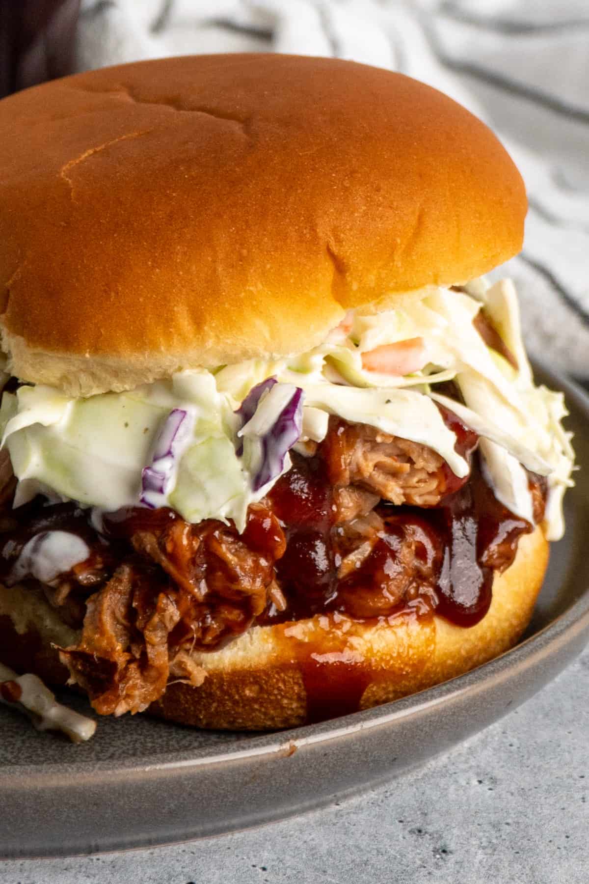 Close up of shredded bbq pork on a bun with coleslaw.