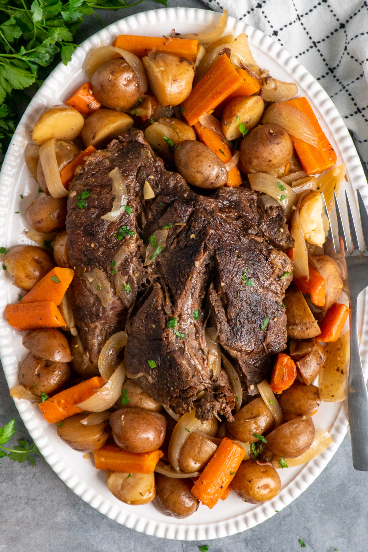 Slow cooker pot roast with potatoes and carrots on a oval serving platter.