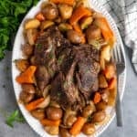 Slow cooker pot roast with potatoes and carrots on a oval serving platter.