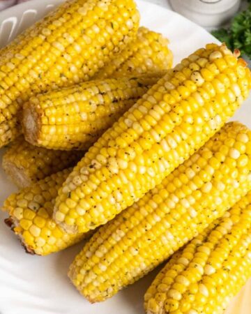 Freshly buttered corn on the cob stacked up on a plate.