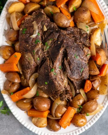 Slow cooker pot roast with potatoes and carrots on a oval serving platter.