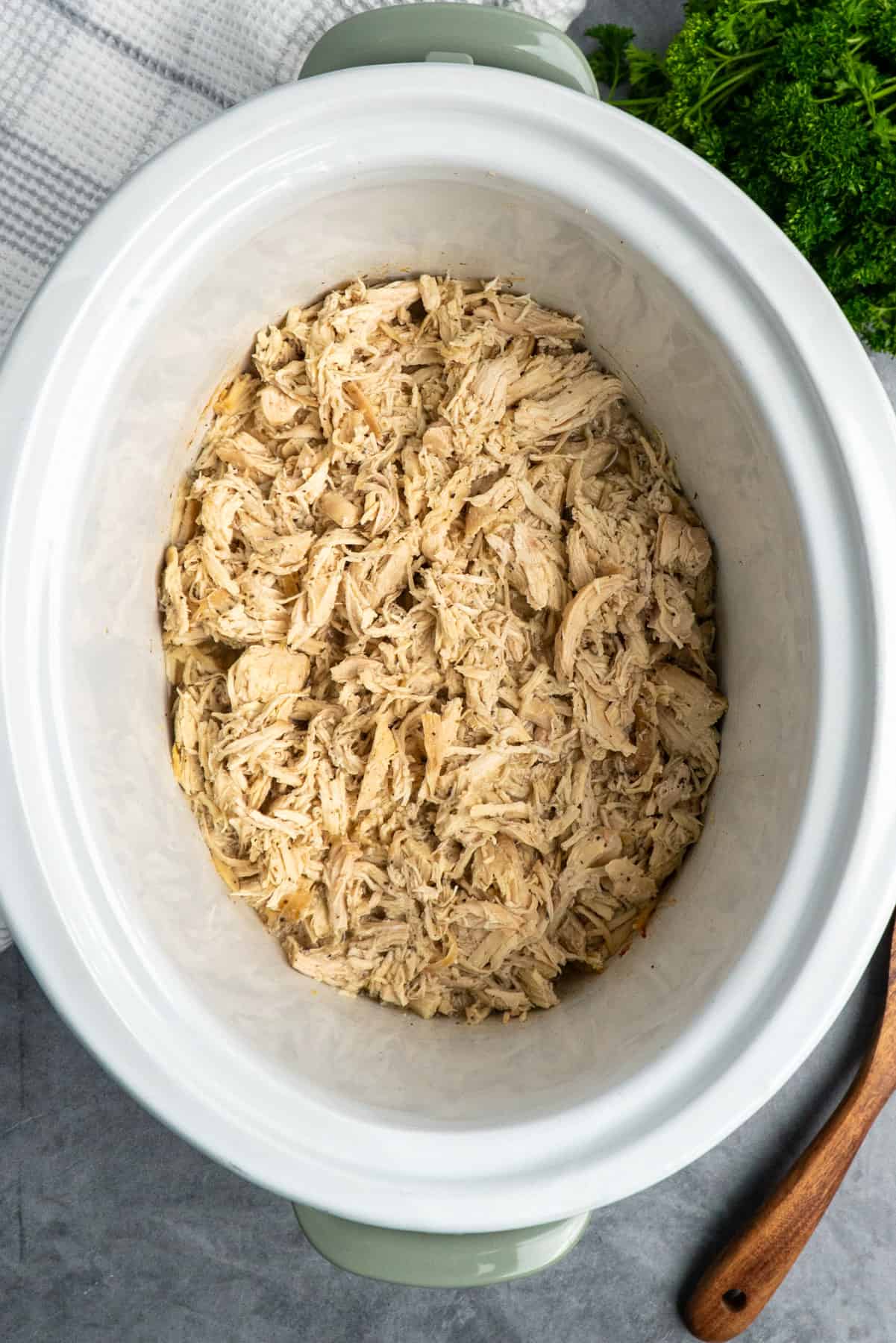 Overhead look at pulled chicken in a white crock pot.