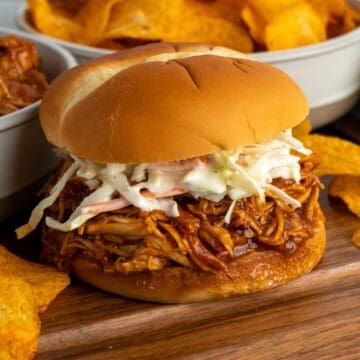 Close-up of crock pot pulled bbq chicken on a bun with cole slaw on top.