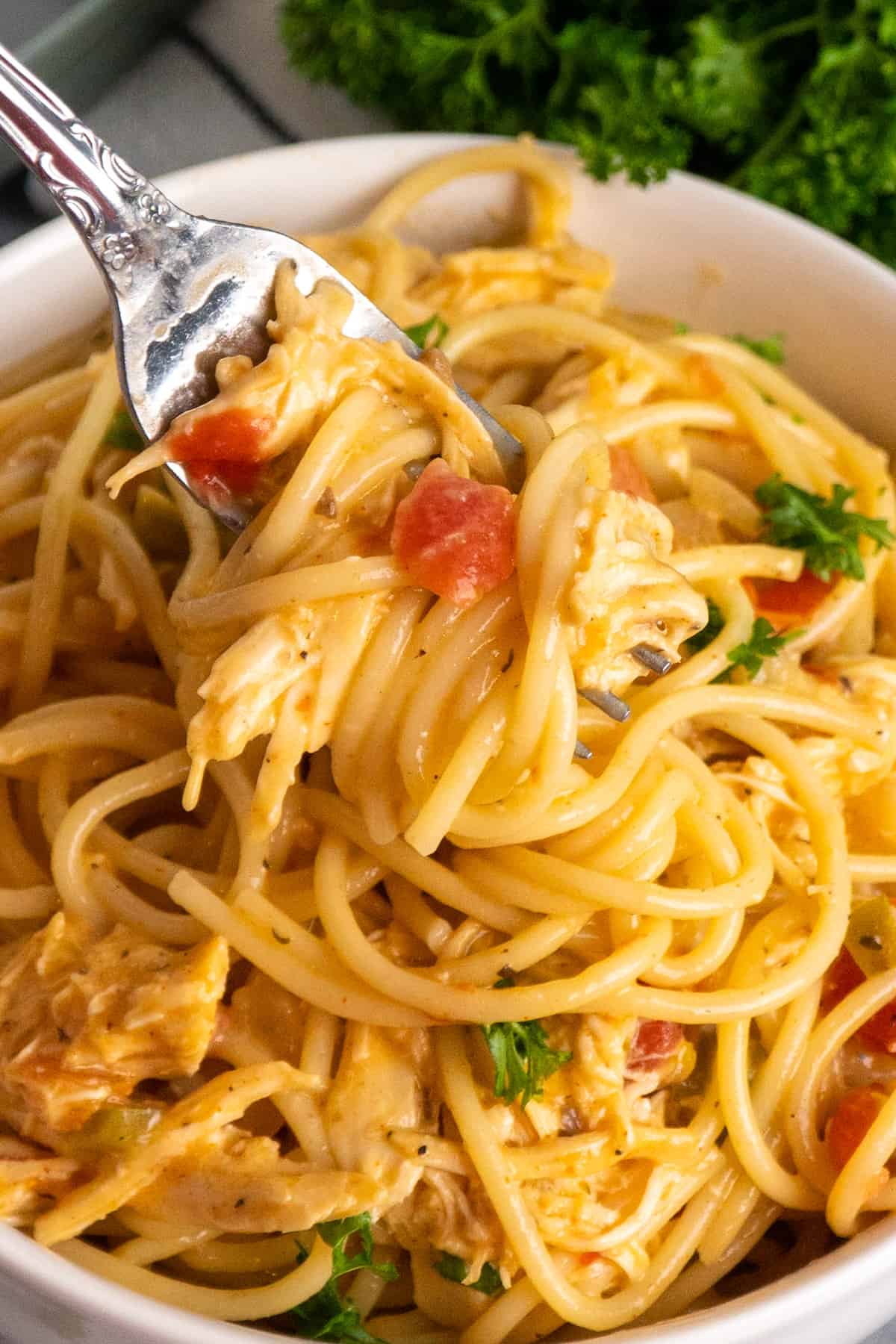 A fork holding a bite of chicken spaghetti with Rotel.