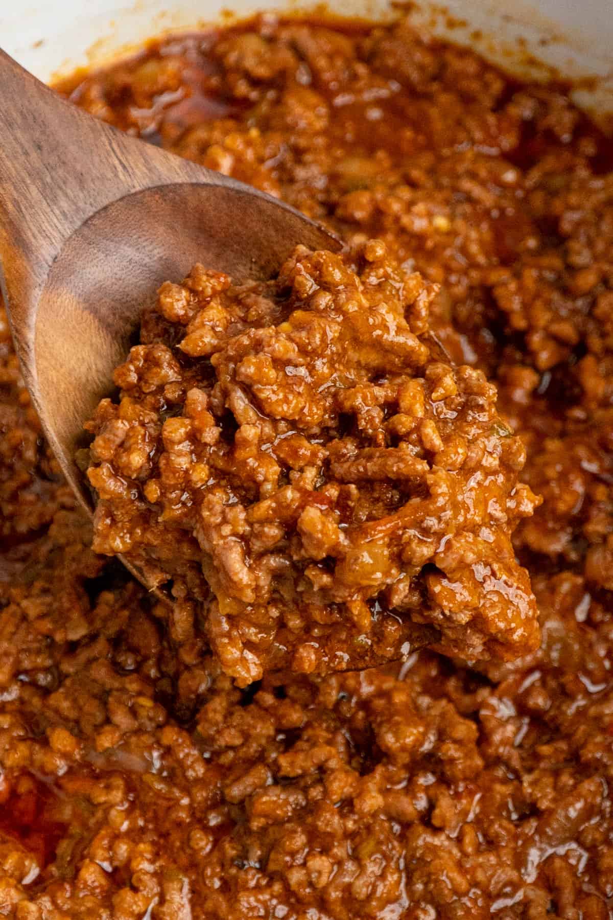 Close-up image of taco meat in a crock pot with a wooden spoon.