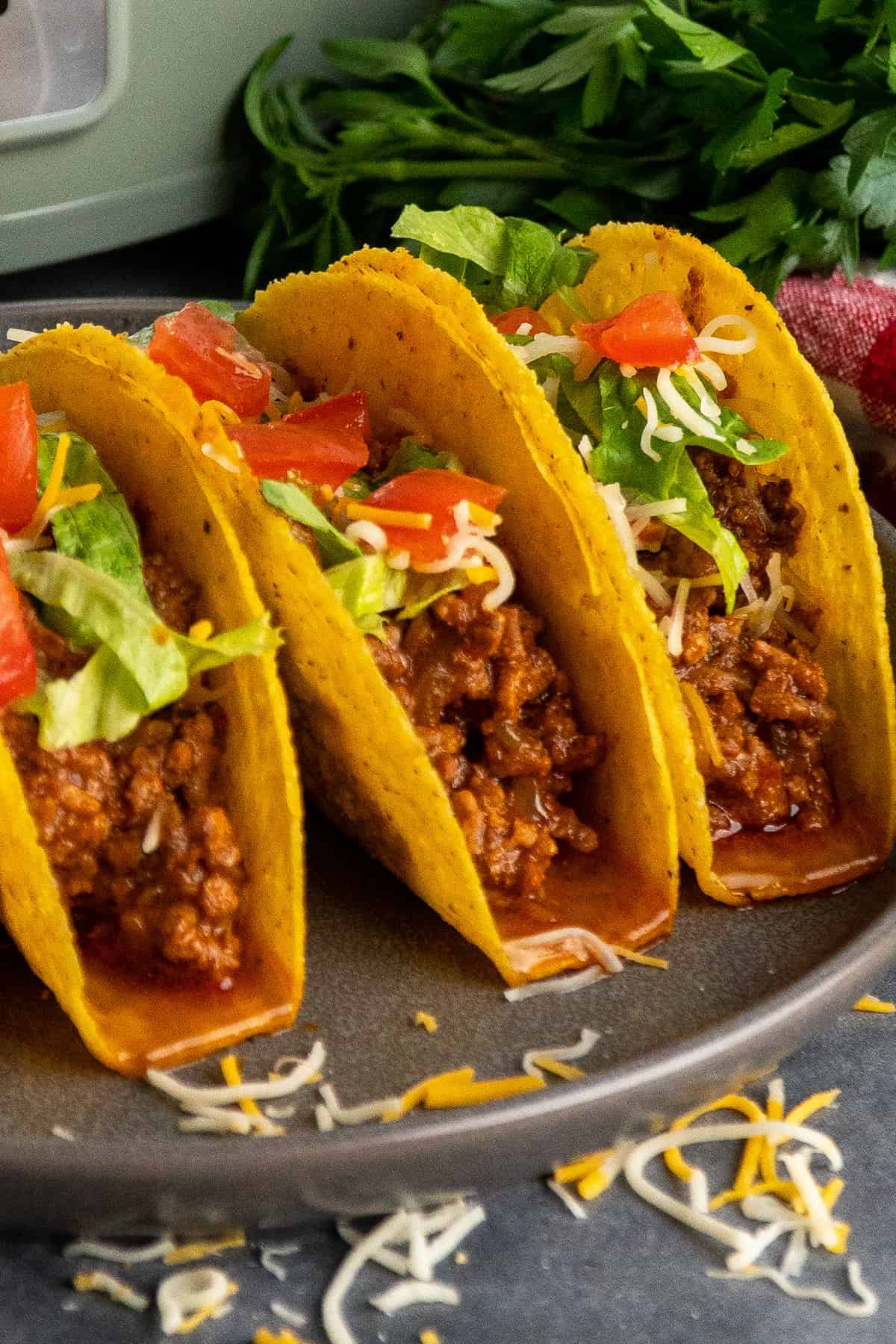 Three ground beef tacos in hard shells on a plate.
