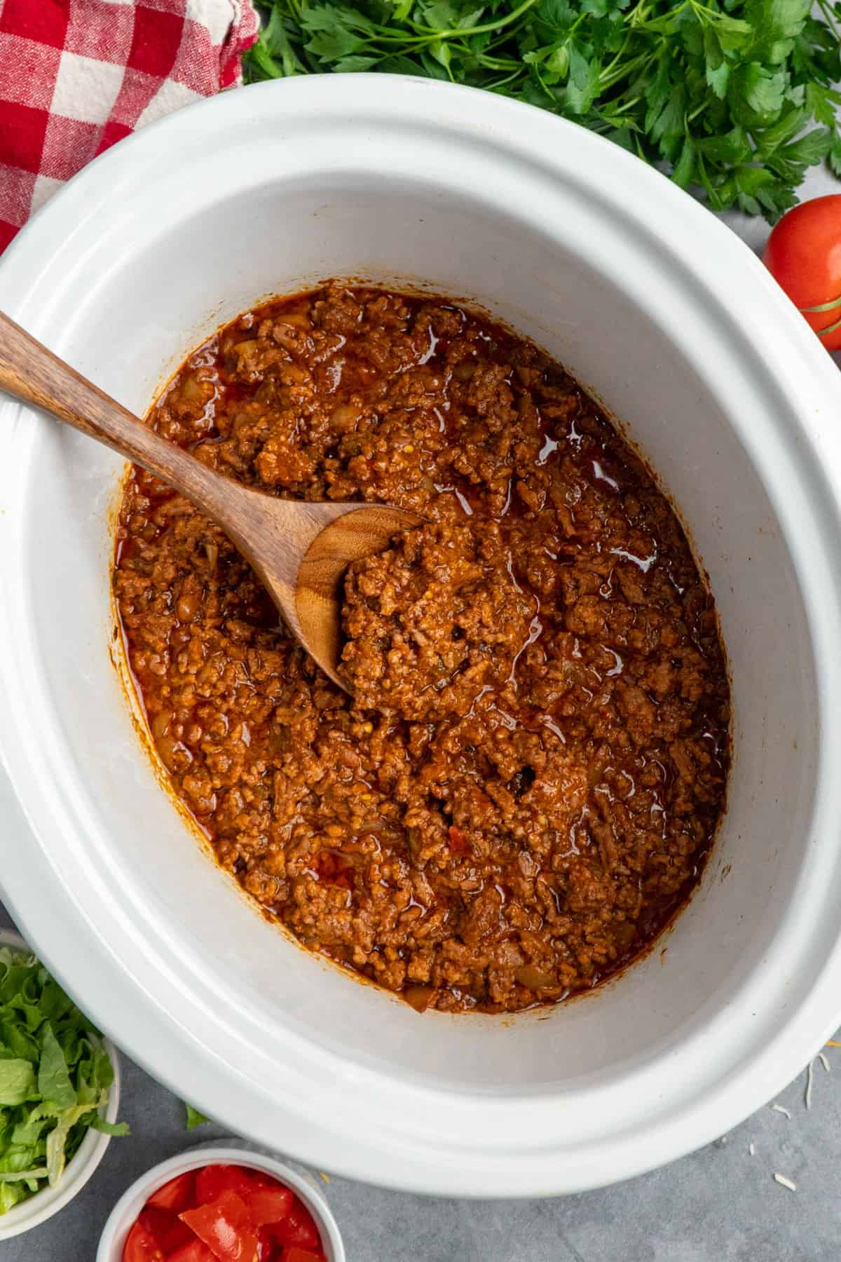 Overhead image of taco meat in a crock pot with a wooden spoon.