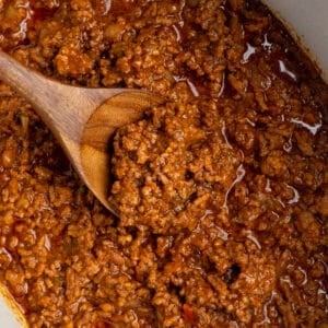 Close-up image of taco meat in a crock pot with a wooden spoon.