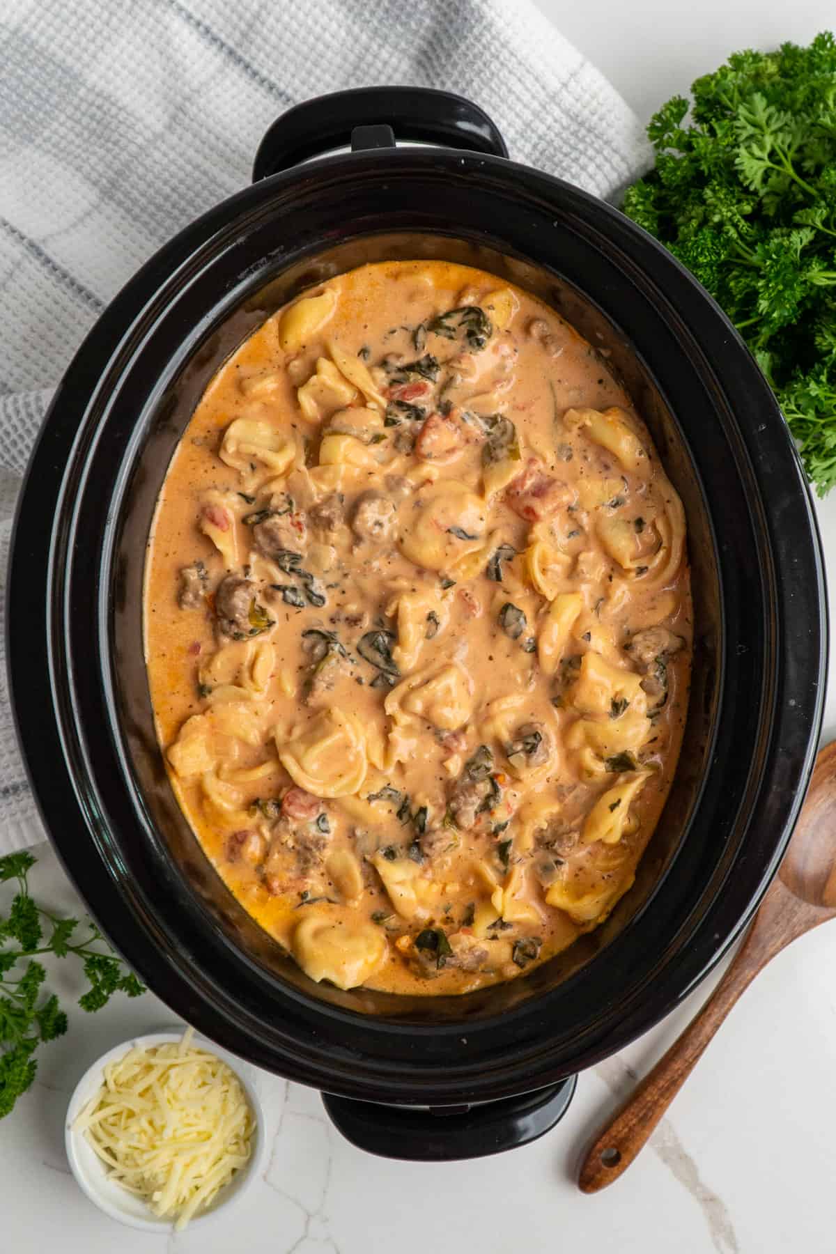 Overhead look at creamy and cheesy tortellini in a slow cooker.