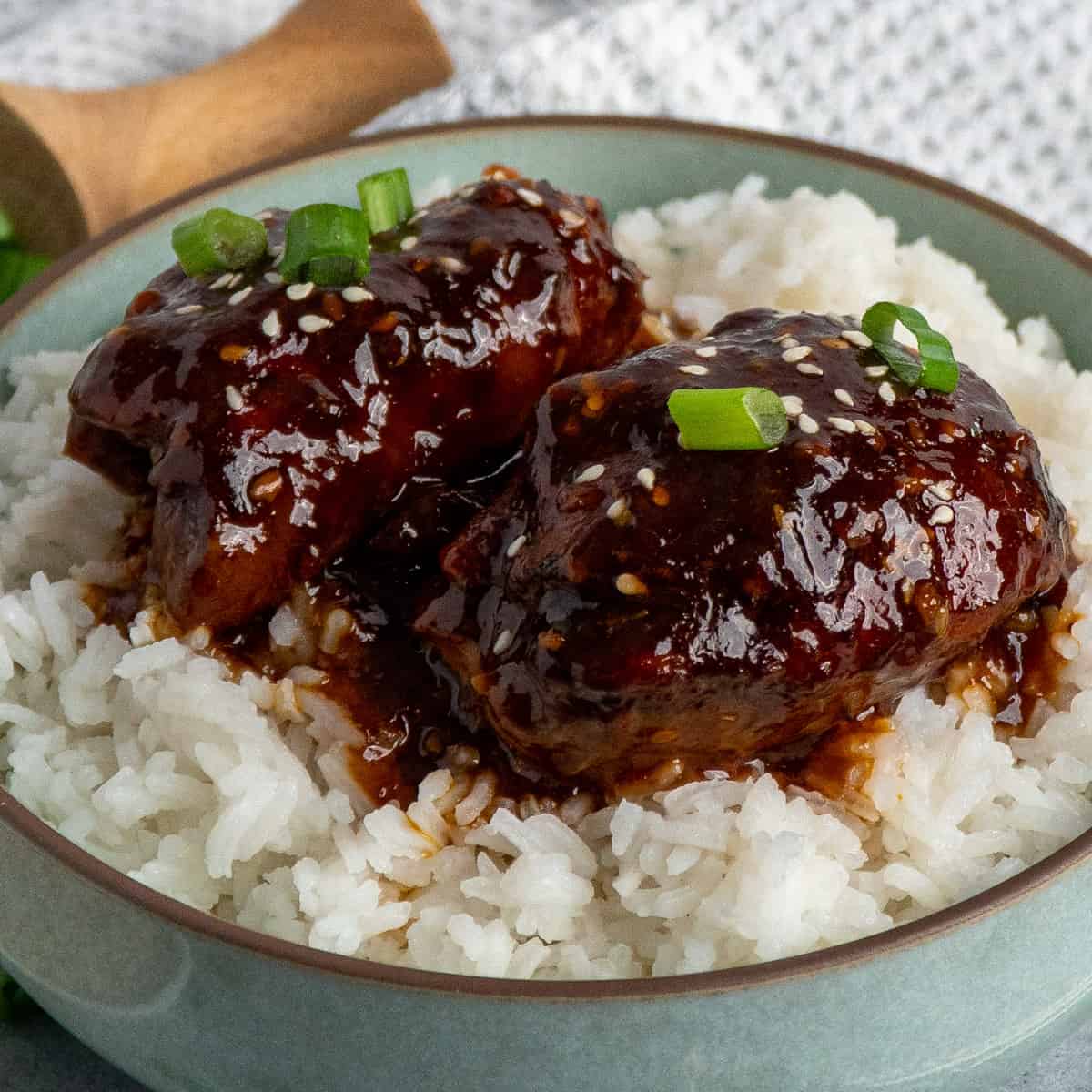 Honey garlic chicken thighs over a bowl of rice.