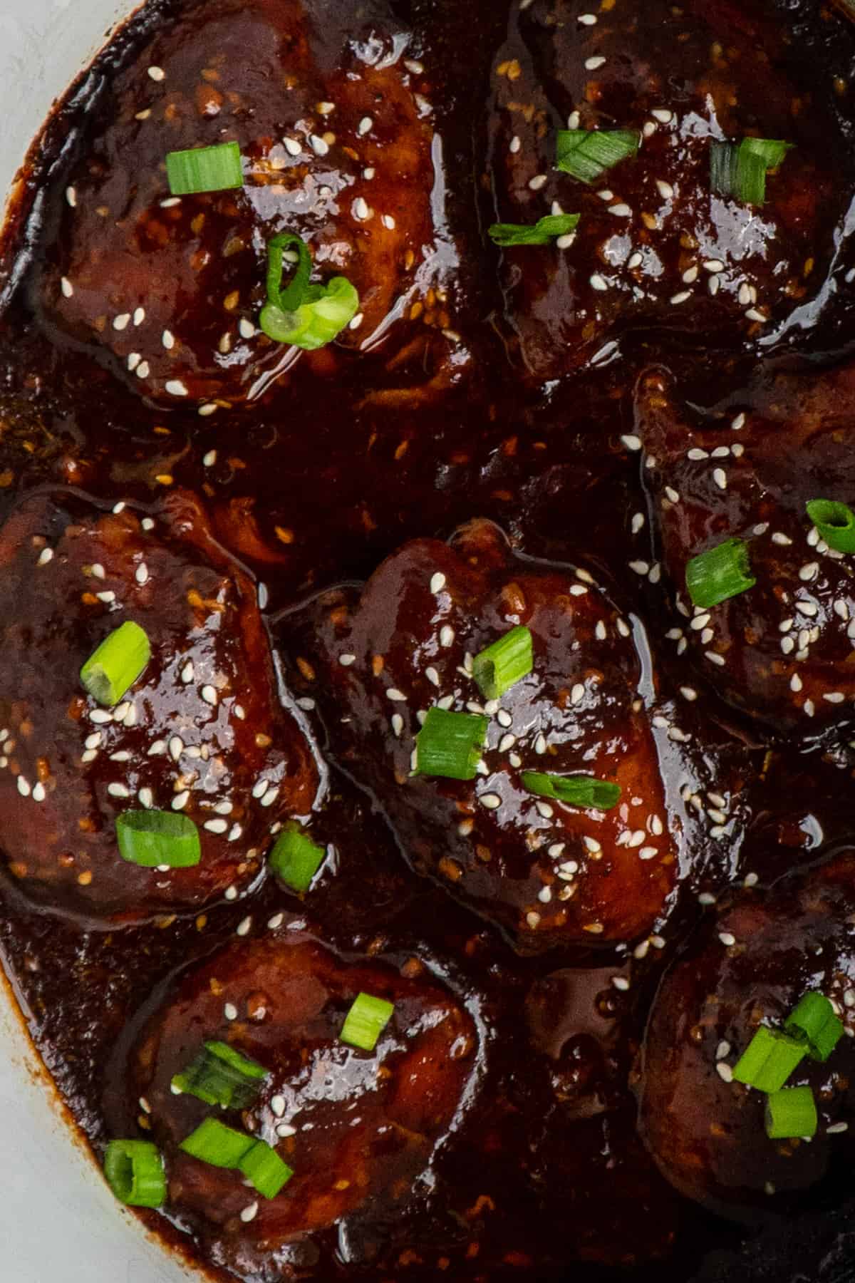 Honey garlic chicken in a crock pot garnished with sesame seeds and green onions.