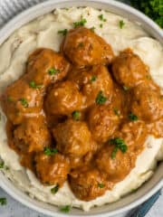 Crock Pot meatballs and gravy over a bowl of mashed potatoes