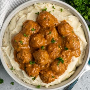 Crock Pot meatballs and gravy over a bowl of mashed potatoes