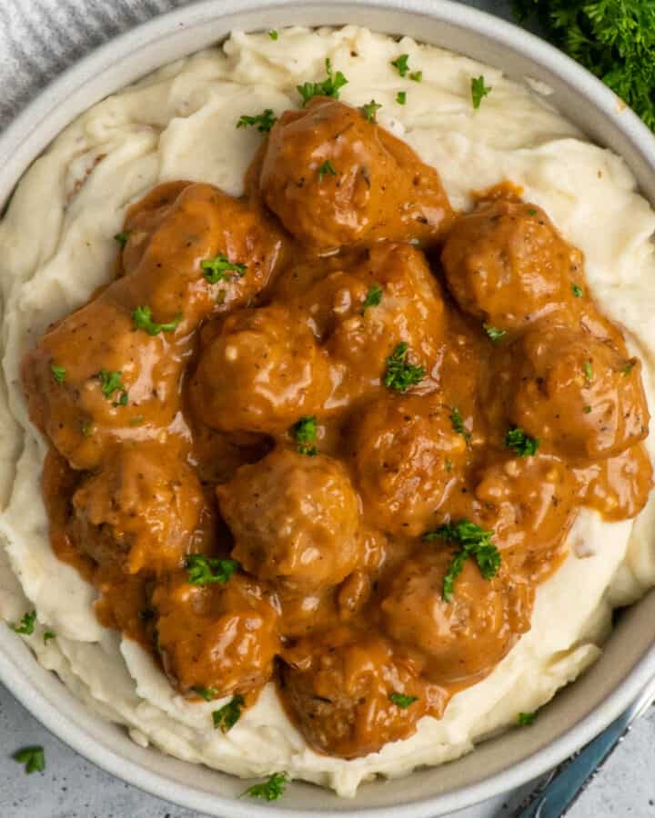 Crock Pot meatballs and gravy over a bowl of mashed potatoes